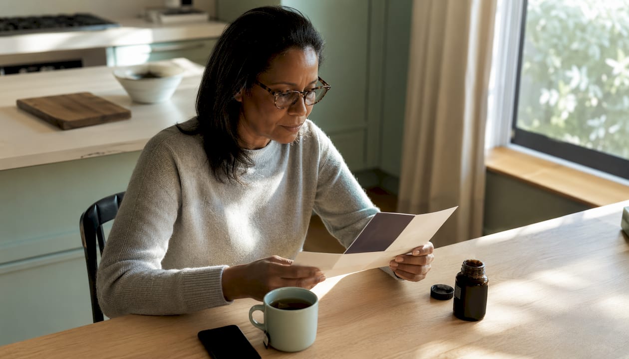 Woman reviewing supplement information at kitchen table