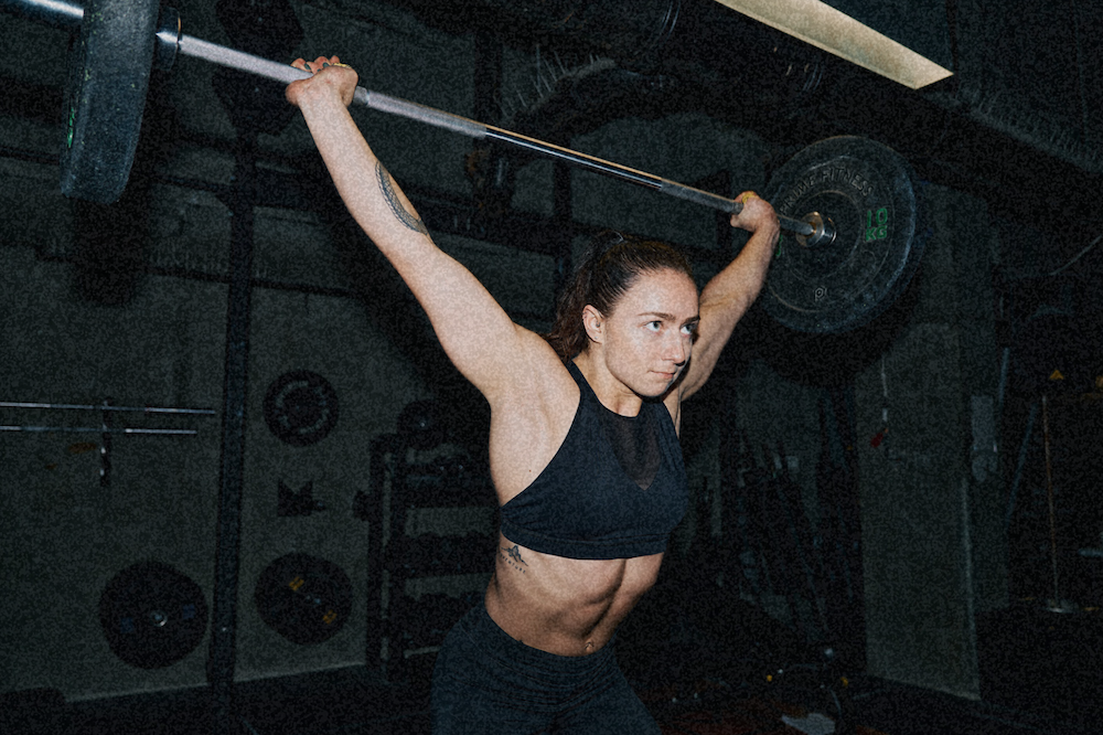 Woman pressing a barbell overhead in a gym