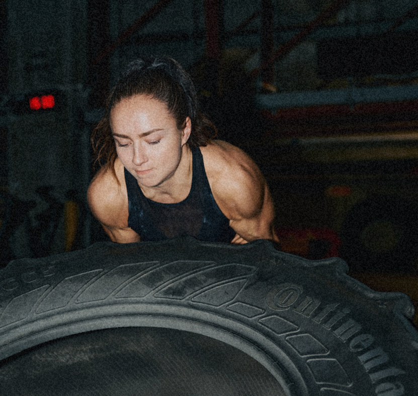 Woman flipping a heavy tyre in a gym