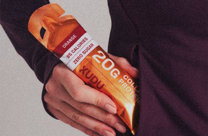 Hand holding a KUDU orange 20g collagen protein sachet