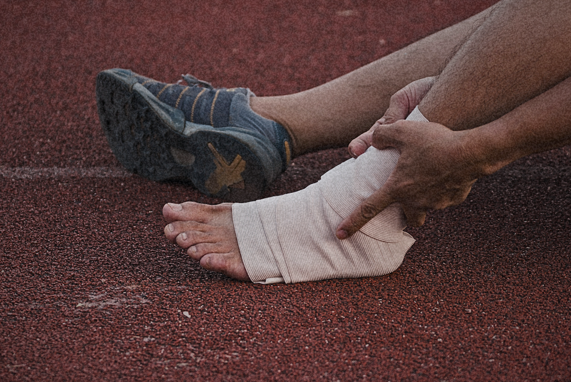 Person wrapping an injured ankle on a running track