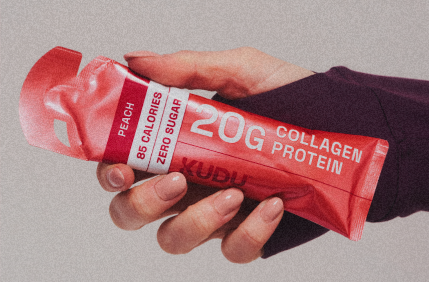 Hand holding a KUDU peach 20g collagen protein sachet