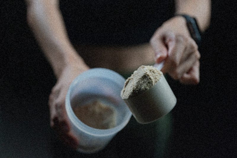 Scooping protein powder into a shaker bottle