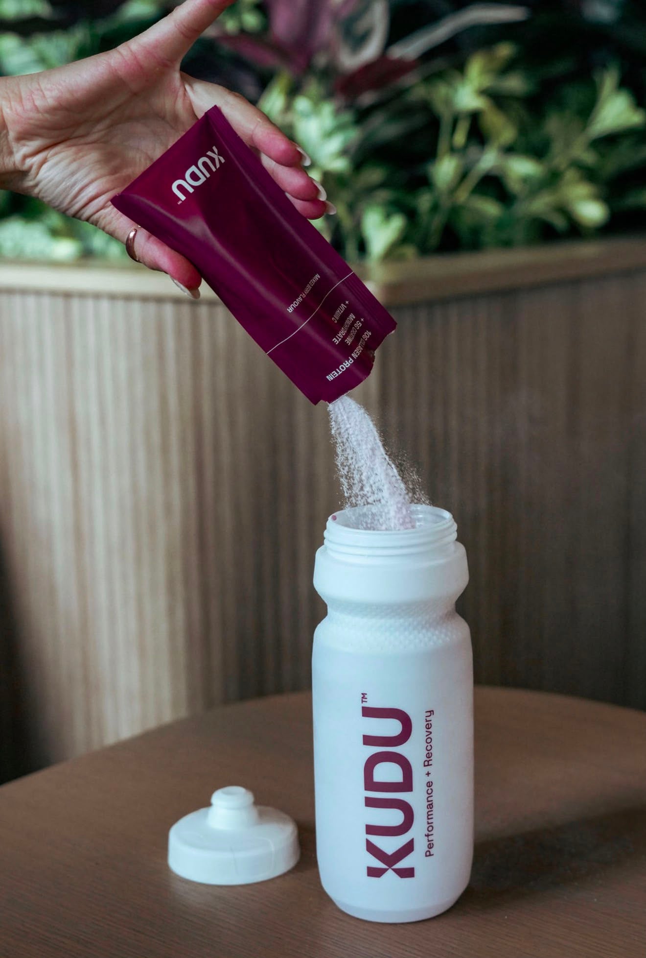 Pouring a KUDU Collagen + Creatine sachet into the Cream White KUDU Water Bottle