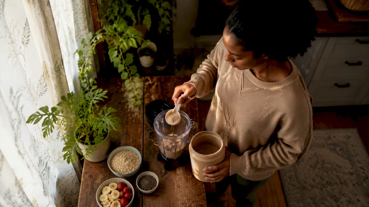 Woman making morning protein shake in kitchen