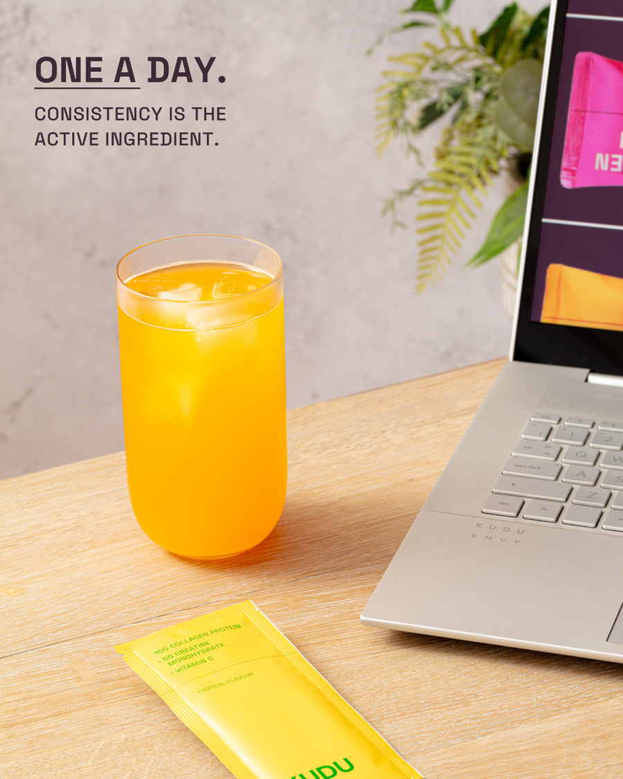 KUDU Collagen + Creatine daily sachet mixed into water beside a laptop — one a day